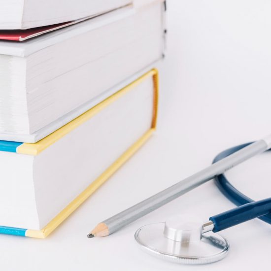 stacked-books-pencil-stethoscope-white-surface (1)